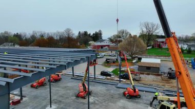 Gordonville, Pennsylvania, 10 Nisan 2025 - İşçiler öğleden sonra bir inşaat alanında çelik kirişleri monte etmek için vinç ve asansör kullanıyorlar. Yapı şekillendikçe ekipman kullanılıyor.