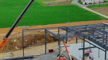 Gordonville, Pennsylvania, 9 Nisan 2025 İşçiler vinç ve metal çerçeveler kullanarak bir bina inşa ediyorlar. Bölgeyi çevreleyen yeşil alanlar. Aktivite gündüz vakti gerçekleşiyor.