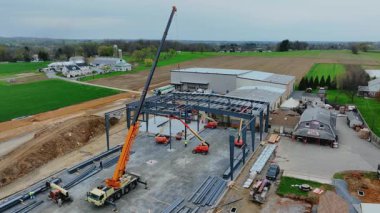 Gordonville, Pennsylvania, 9 Nisan 2025 - işçiler kırsal alanda yeni bir bina inşa ediyorlar. Arazide hareket eden vinçler ve araçlar var. İş bir yerde geçiyor.