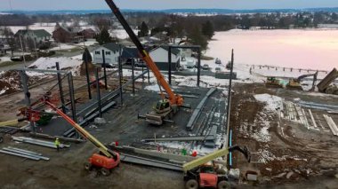 Gordonville, Pennsylvania, 25 Şubat 2026 işçiler göl kenarında yeni bir bina inşa ediyorlar. Turnalar malzemeleri ve aletleri hareket ettirir. Süreç kışın gün ışığında gerçekleşir..