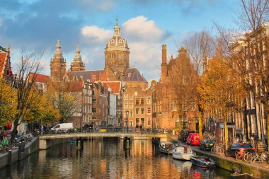 Amsterdam, Hollanda - 12 Kasım 2015: Amsterdam, Hollanda 'da arka planda sonbahar ağaçları ve St. Nicholas kilisesi bulunan Kanal.