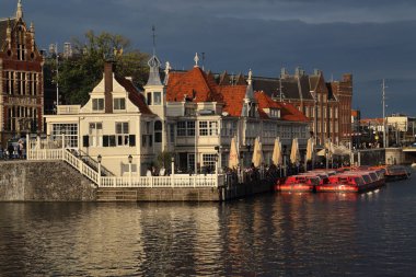 Amsterdam, Hollanda - 11 Ağustos 2017: Amsterdam, Hollanda 'da 11 Ağustos 2017' de gün batımının ışığında tarihi restoran ve tur tekneleri