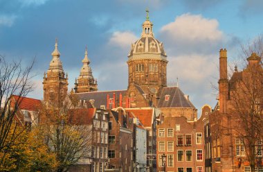 St. Nicholas Kilisesi ve sonbahar ağaçları ve Amsterdam, Hollanda 'da bulutlu gökyüzü