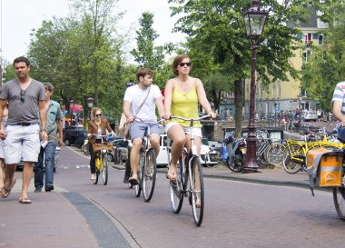 Turistler Amsterdam'da bisiklet üzerinde