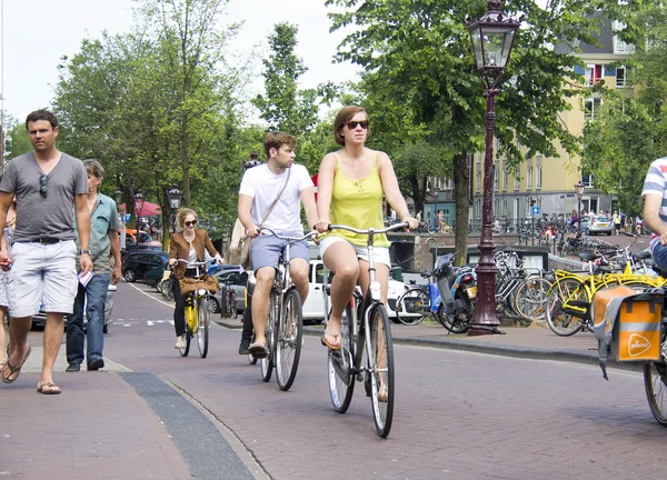 Turistler Amsterdam'da bisiklet üzerinde