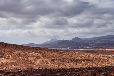 İspanya 'nın Kanarya Adaları, Tenerife, El Medano yakınlarındaki Doğal Montana Roja volkanik manzarası. Altın kum tepeleri ve dramatik volkanik dağ Atlantik kıyısında çarpıcı bir çöl manzarası yaratır. Hiki ile bilinen korunan doğal alan.