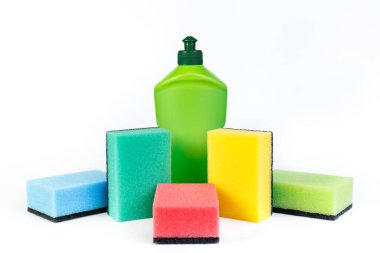 Bir şişe bulaşık deterjanı ve beyaz arka planda renkli süngerler..