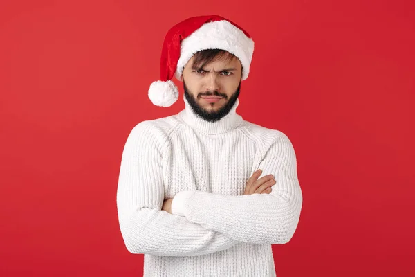 Homem hipster perturbado usa chapéu de Papai Noel sobre fundo vermelho. Conceito de Natal e Ano Novo. — Fotografia de Stock