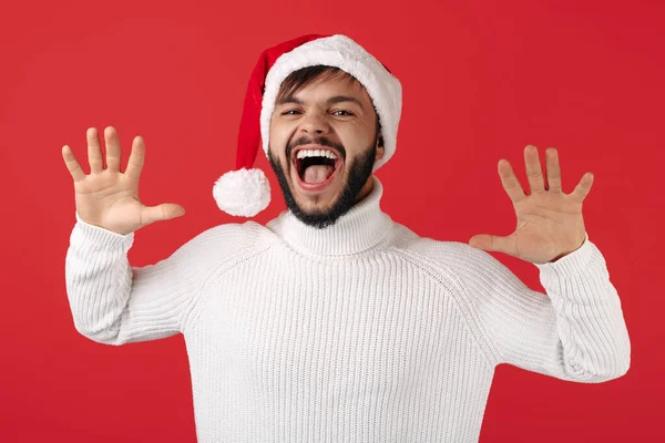 Surpris hipster homme porte santa claus chapeau célébrer le succès sur fond rouge. Noel et Nouvel An concept. — Photo