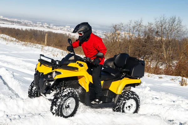 Extremal driver driving his ATV quad bike stand in heavy snow with deep wheel track.