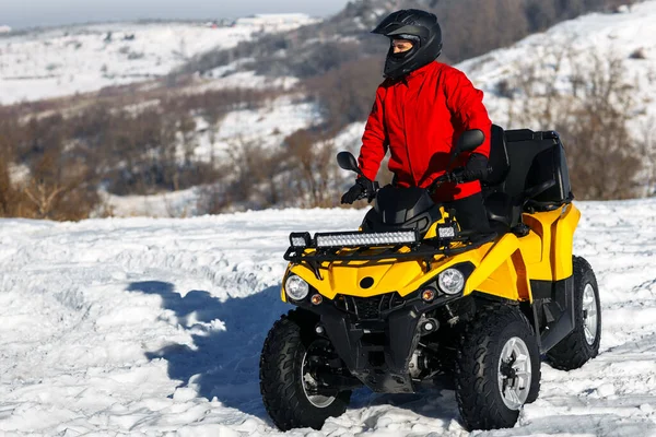 Νεαρός οδηγός στο κιόσκι ATV quad ποδήλατο σε βαρύ χιόνι με βαθιά τροχιά τροχό. Moto χειμερινά αθλήματα. — Φωτογραφία Αρχείου