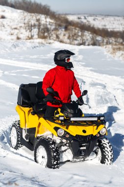 ATV bisikletli genç adam, yoğun kar altında, derin tekerlek yolu ile ayakta duruyor. Moto kış sporları.