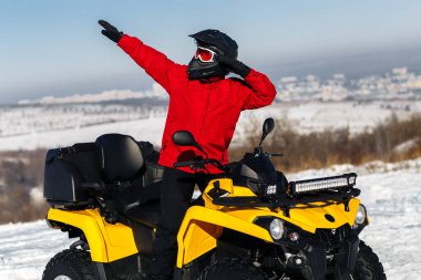 ATV 'nin dört tekerlekli bisiklet standına sürtünen genç bir sürücü. Moto kış sporları.