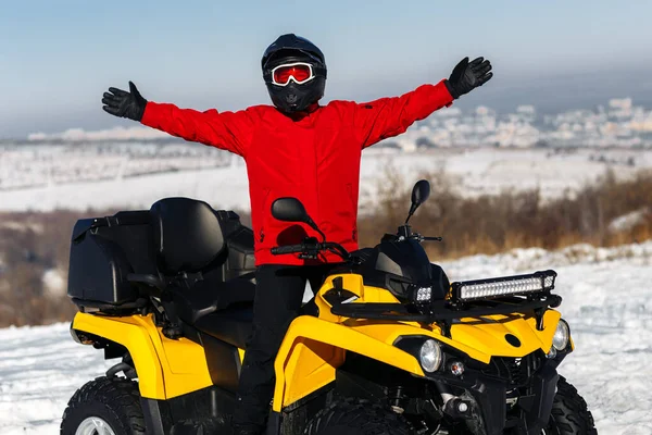 ATVクワッドバイクにポーズをとっている若い男ドライバーは深いホイールトラックで大雪の中に立っている。元ウィンタースポーツ. — ストック写真