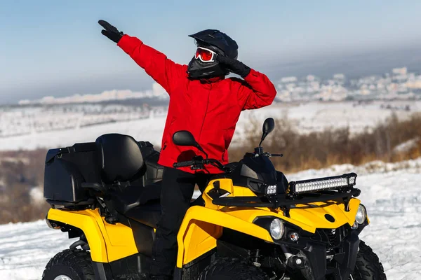 ATVクワッドバイクに乗っていた若い男ドライバーは、深いホイールトラックと大雪の中に立っています。元ウィンタースポーツ. — ストック写真
