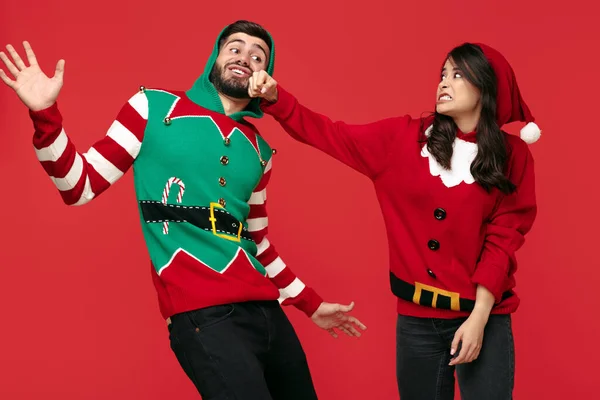 Imagem louca de casal vestido com camisolas engraçadas de Natal sobre fundo vermelho. Dá um murro no maxilar. — Fotografia de Stock