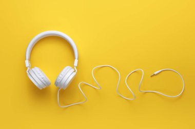 Sarı arka planda modern beyaz kulaklık. Müzik konsepti.