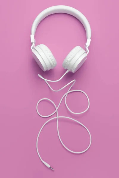 Cuffia bianca fredda su sfondo rosa. Concetto musicale. — Foto Stock