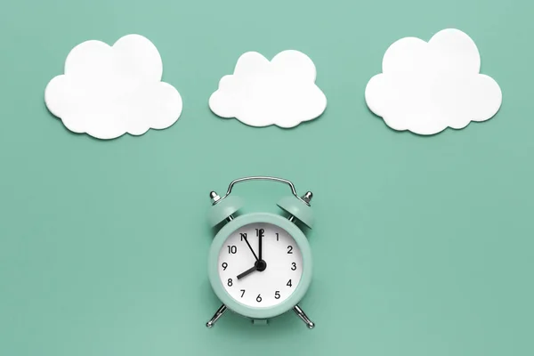 Classic round alarm clock and white clouds on the mint green background. — Stock Photo, Image