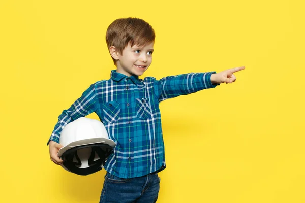 快乐的小男孩工程师或建筑师，戴着保护头盔，指指点点黄色背景的手指. — 图库照片