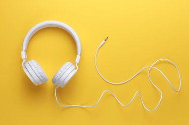 Sarı arka planda modern beyaz kulaklık. Müzik konsepti.