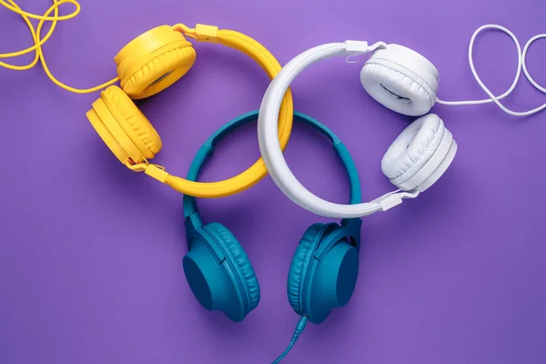 三部耳机，背景为紫色。音乐概念. — 图库照片
