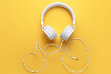 Sarı arka planda beyaz kulaklığın fotoğrafı. Müzik konsepti.
