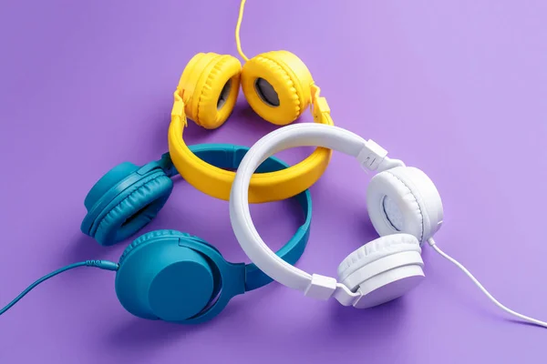 Set of three headphones over purple background. Music concept. — Stock Photo, Image