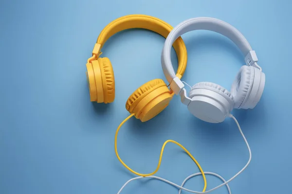 Dos elegantes auriculares sobre fondo azul. Concepto musical. — Foto de Stock