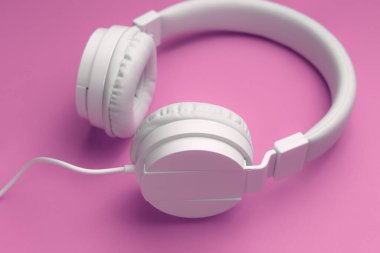 Pembe arka planda modern beyaz kulaklık. Müzik konsepti.