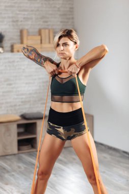 Sportif sarışın kadın spor salonunda bantlarla egzersiz yapıyor..