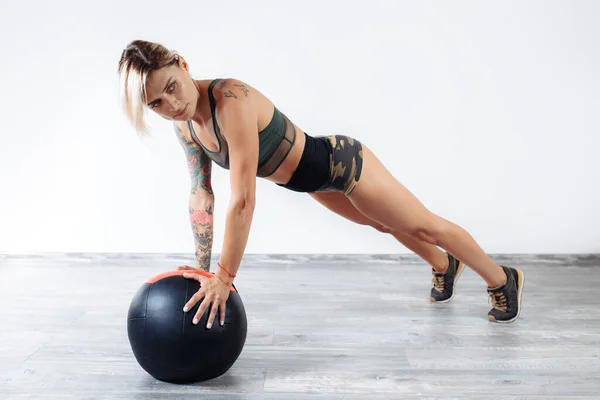 Fit young blonde woman doing exercise with medicine ball in gym. — Stock Photo, Image