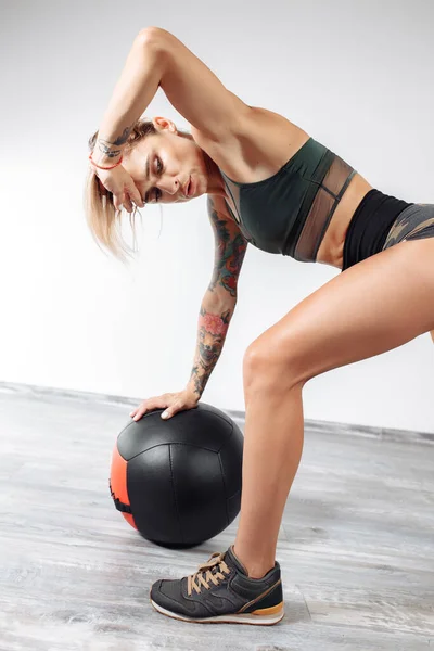 Спортивная молодая блондинка отдыхает после тренировки с мячом в спортзале. — стоковое фото