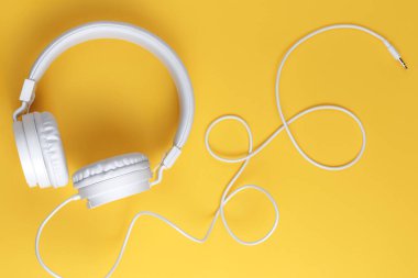 Sarı arka planda beyaz kulaklık resmi. Müzik konsepti.