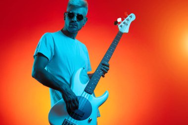 Kendine güvenen sarışın hippi beyaz gitarı neon ışıklarla eziyor. Rock müzik konsepti.
