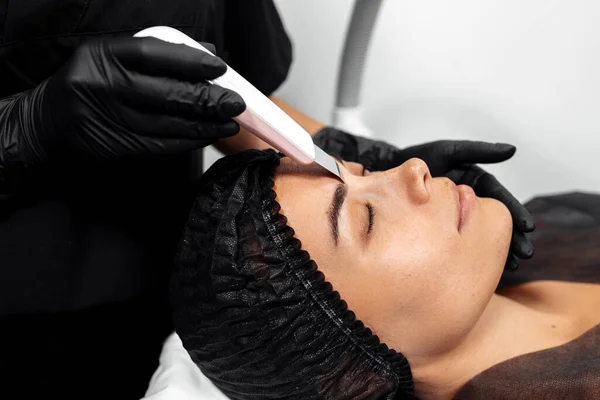 Cosmetólogo hacer cara mientras procedimiento cavitación por ultrasonido o descamación facial en el gabinete de cosmetología. —  Fotos de Stock
