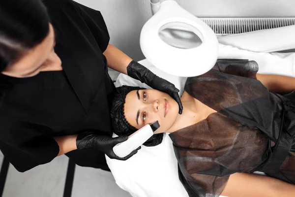 Kosmetolog zrobić twarz podczas zabiegu USG kawitacji lub peeling twarzy w gabinecie kosmetologii. — Zdjęcie stockowe