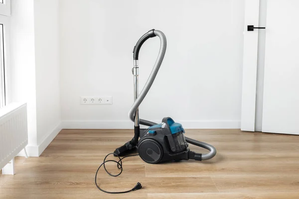 Modern blue vacuum cleaner on the wooden floor in living room. — Stock Photo, Image