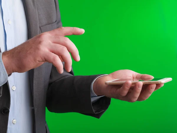A businessman's hand with a modern phone on green background