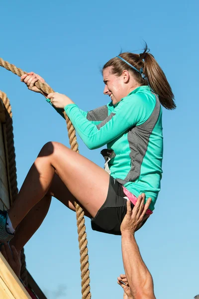 Vrouw strijd klimmuur met touw In Extreme hindernissenparcours — Stockfoto