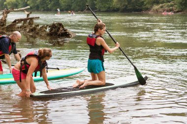 Genç kadın Paddleboard Chattahoochee nehir üzerinde diz çöker