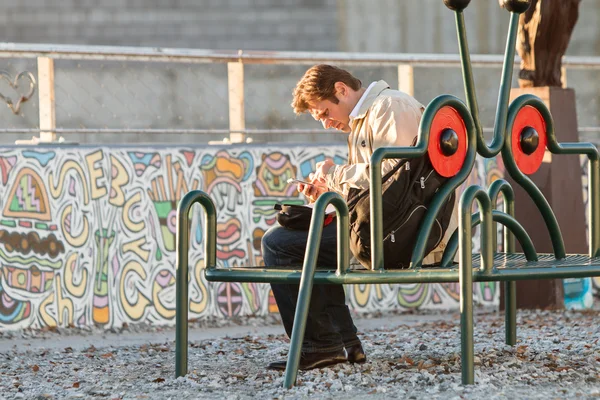 Mann bearbeitet sein Smartphone sitzend auf Gürtellinie — Stockfoto