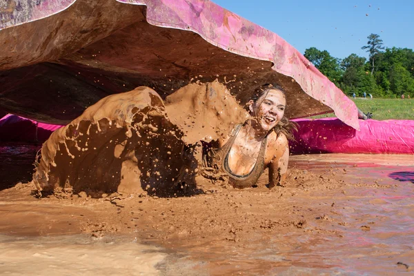 Frau planscht bei Schlammlauf-Veranstaltung durch schlammiges Wasser — Stockfoto