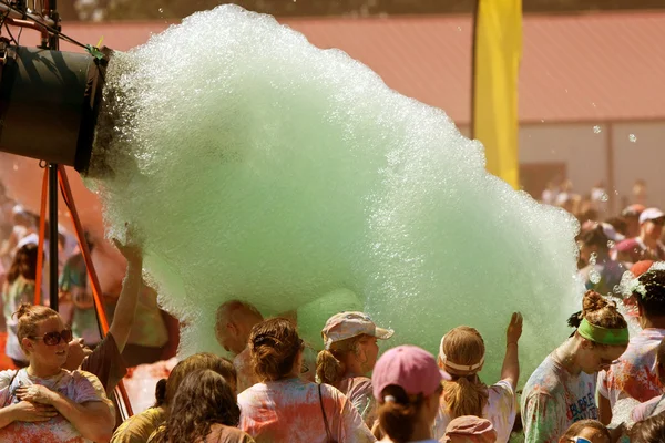 La gente cammina attraverso il flusso di schiuma verde a bolla Palooza — Foto Stock