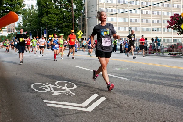 Äldre kvinna körs i atlanta peachtree road race — Stockfoto