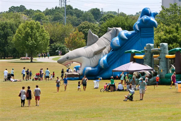 Las familias disfrutan de una diapositiva inflable gigante del tiburón en el patio del festival —  Fotos de Stock