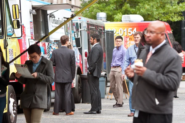 Människor vänta i kö till beställa måltider från mat lastbilar — Stockfoto