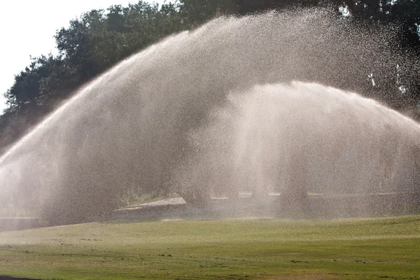 Sprinkler übergießen Golfplatz Fairway mit Wasser — Stockfoto