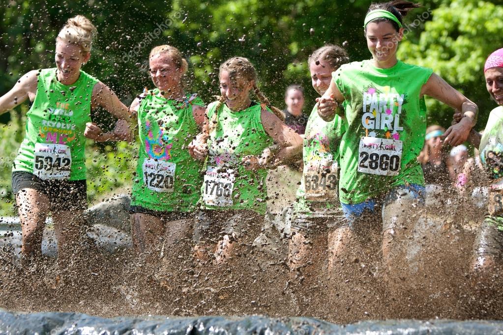 2012: A group of young women join arms and stomp through a mud pit together...