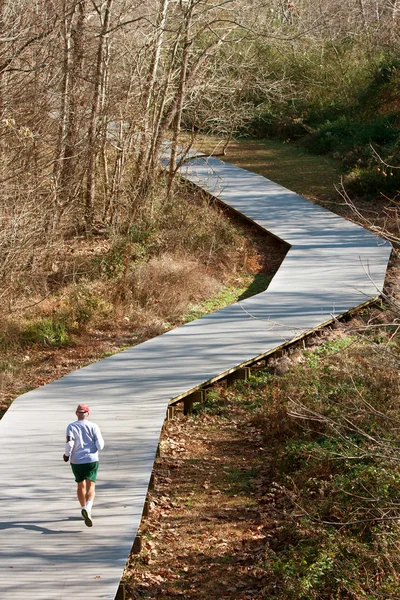 木製デッキのトレイルをジョギングで年配の男性が実行されます。 — ストック写真